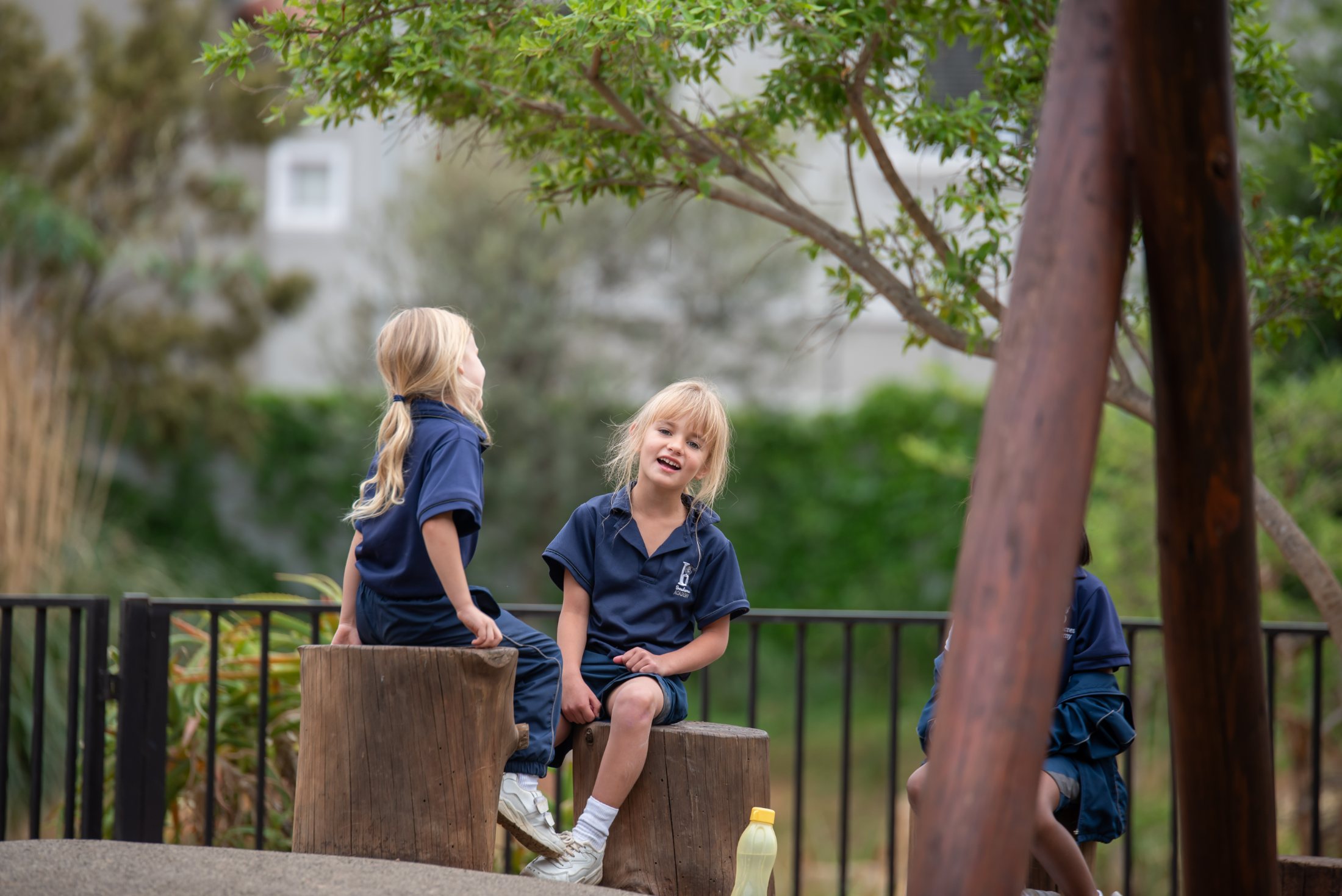 Two Broadacres preschoolers chatting on tree-stump benches