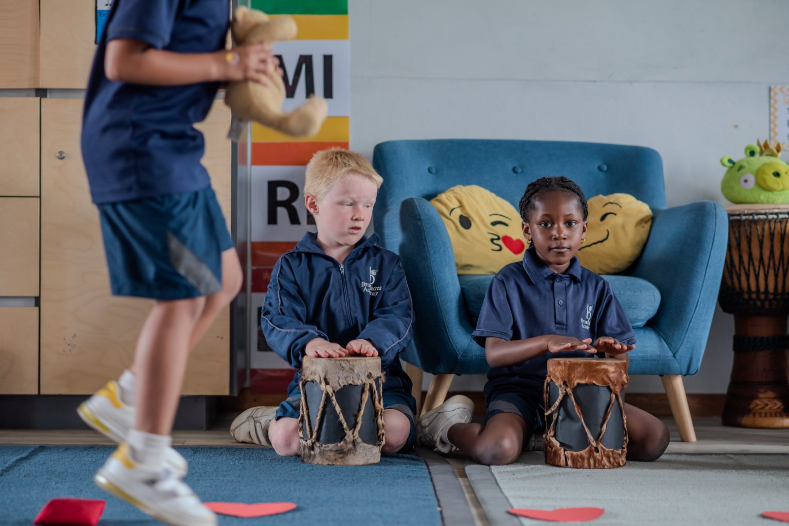 Two Junior Prep children drumming on African hand drums during a music lesson