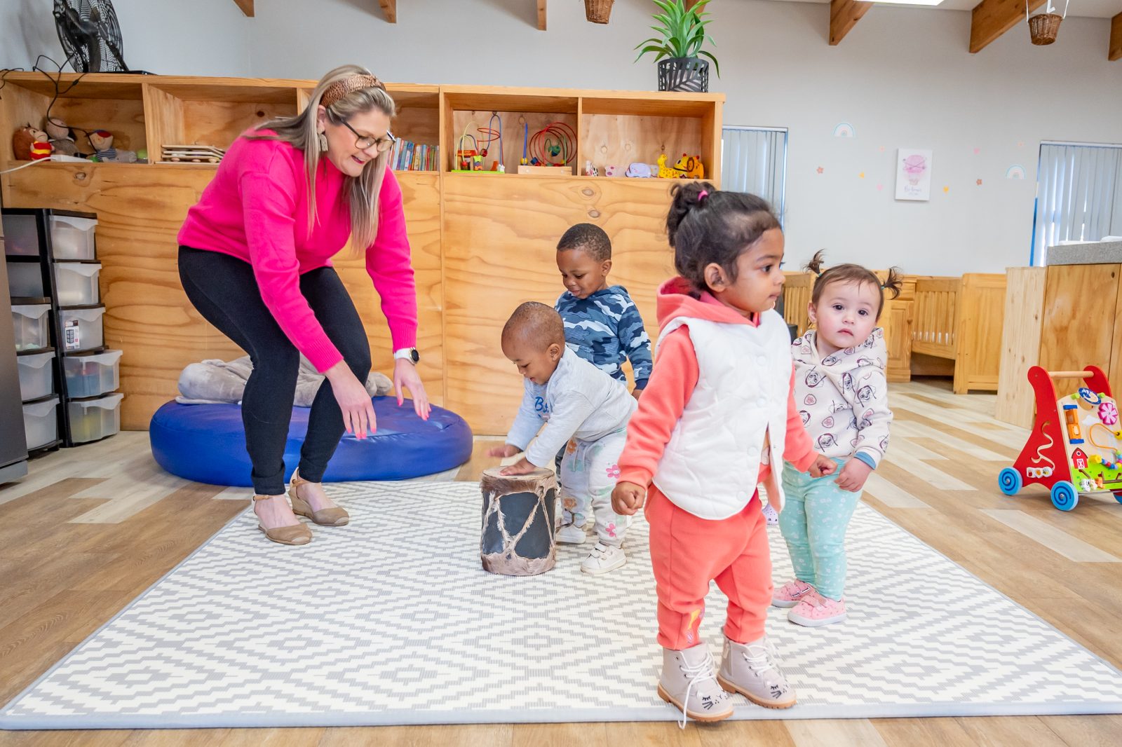 A teacher engaging with toddlers in a sunny Preschool classroom