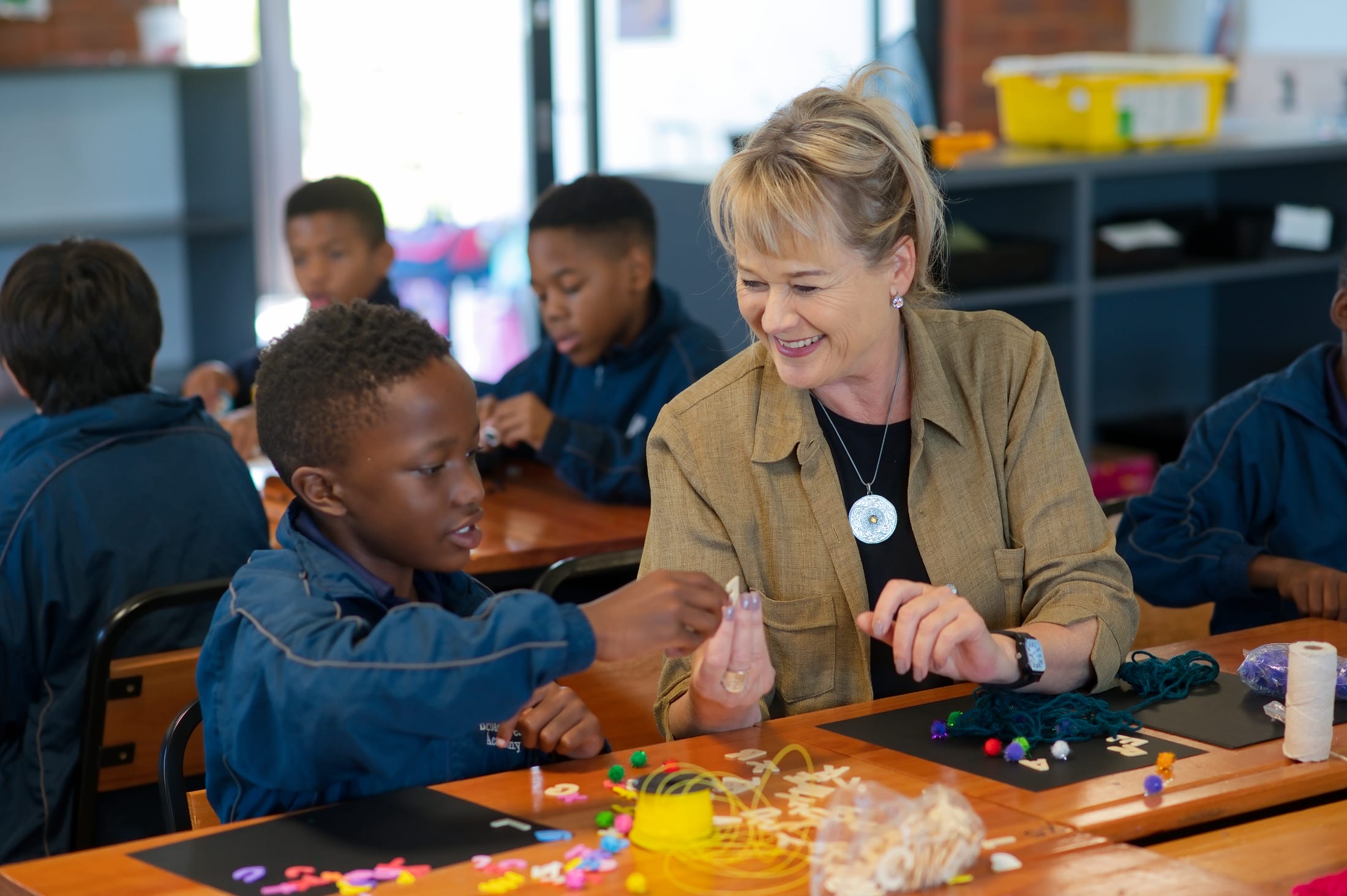 A Broadacres child threading coloured beads during a hands-on activity